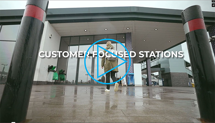 Screenshot of a of a woman walking towards a station with the text 'customer focused stations' linking to a video